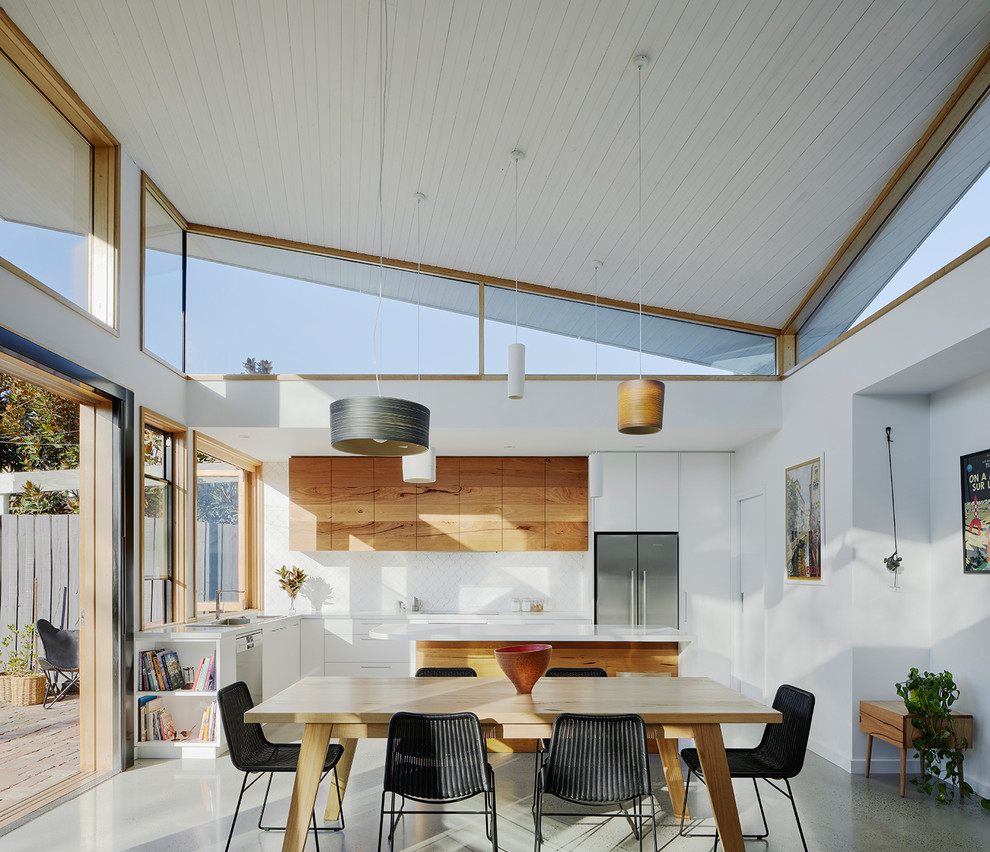 This is an example of a mid-sized contemporary l-shaped eat-in kitchen in Melbourne with white splashback, multiple islands, grey floor, a drop-in sink, flat-panel cabinets, medium wood cabinets and stainless steel appliances.