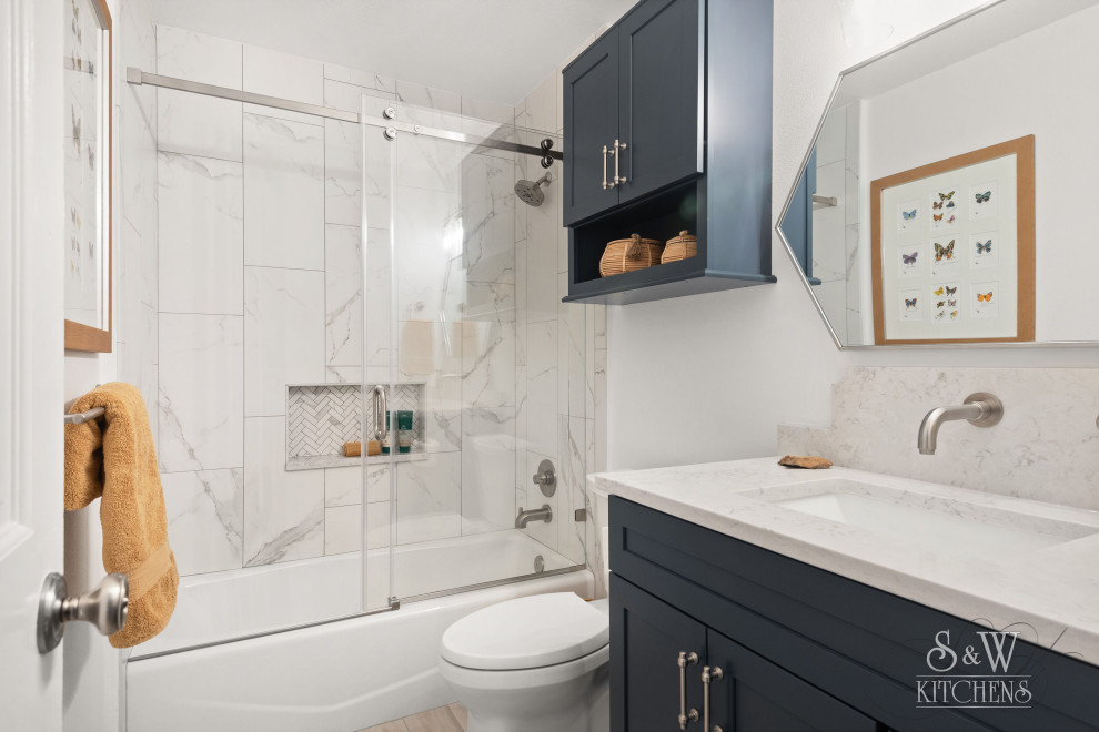Свежая идея для дизайна: маленькая детская ванная комната в скандинавском стиле с фасадами в стиле шейкер, синими фасадами, ванной в нише, душем над ванной, раздельным унитазом, серой плиткой, керамогранитной плиткой, белыми стенами, полом из керамогранита, врезной раковиной, столешницей из искусственного кварца, бежевым полом, душем с раздвижными дверями, серой столешницей, нишей, тумбой под одну раковину и встроенной тумбой для на участке и в саду - отличное фото интерьера