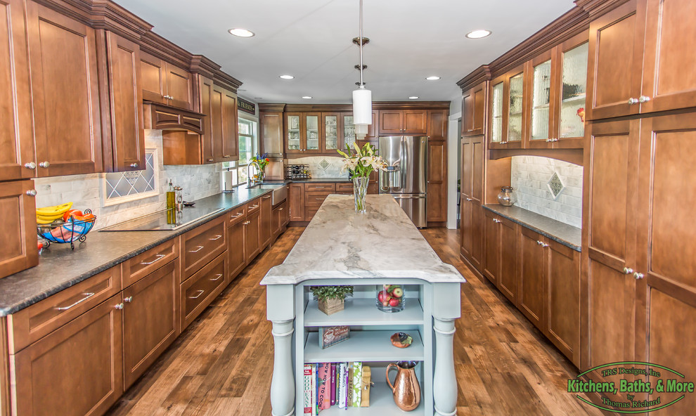 This is an example of a large transitional kitchen in Philadelphia with a farmhouse sink, flat-panel cabinets, medium wood cabinets, granite benchtops, white splashback, subway tile splashback, stainless steel appliances, vinyl floors and with island.