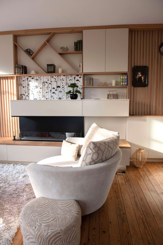 Foto di un piccolo soggiorno chic aperto con libreria, pareti beige, pavimento in legno massello medio e camino bifacciale