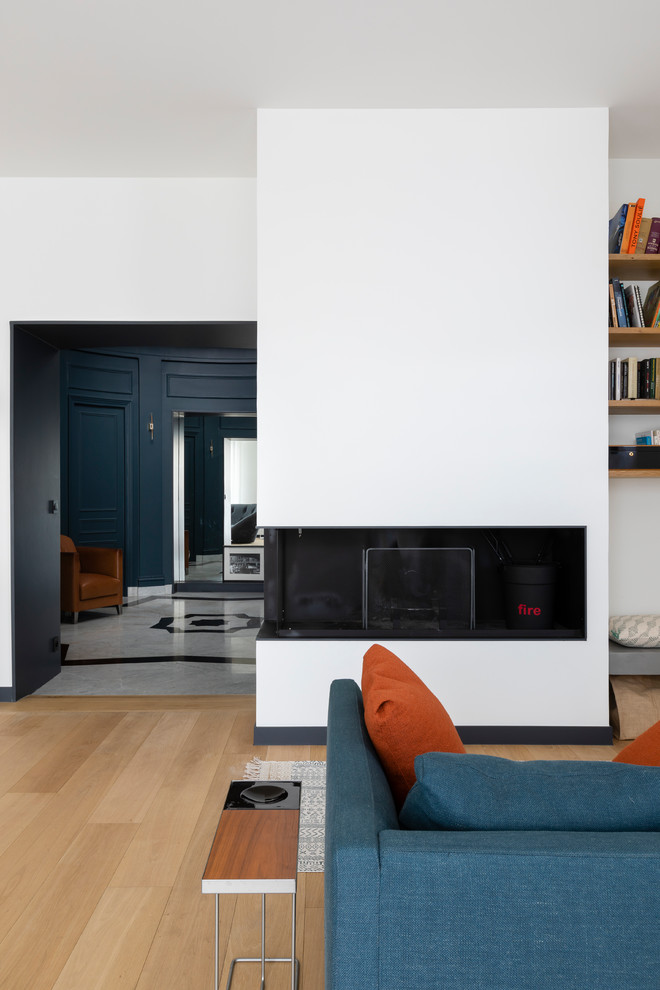 This is an example of a mid-sized contemporary open concept living room in Paris with white walls, light hardwood floors, a standard fireplace and no tv.