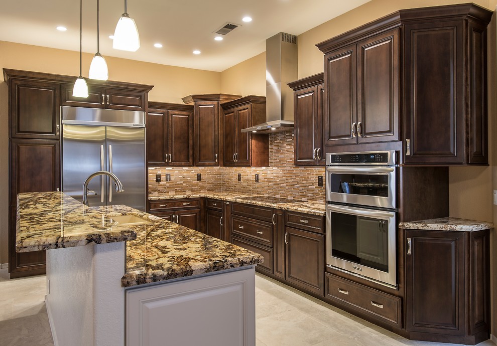 Open concept kitchen - mid-sized transitional l-shaped ceramic tile open concept kitchen idea in Phoenix with an undermount sink, raised-panel cabinets, dark wood cabinets, granite countertops, brown backsplash, glass tile backsplash, stainless steel appliances and an island