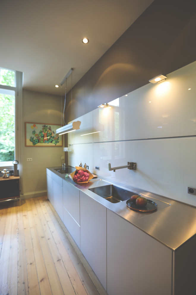 На фото: кухня-гостиная в современном стиле с одинарной мойкой, серыми фасадами, столешницей из нержавеющей стали и серой столешницей с