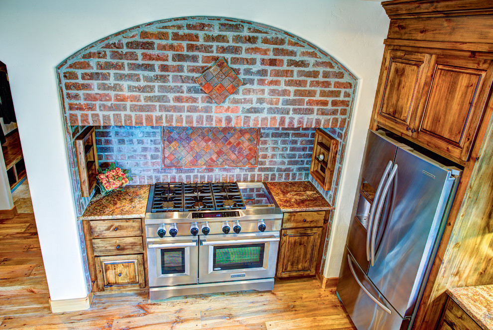 Large mountain style u-shaped medium tone wood floor kitchen pantry photo with a drop-in sink, glass-front cabinets, medium tone wood cabinets, beige backsplash, stainless steel appliances and an island