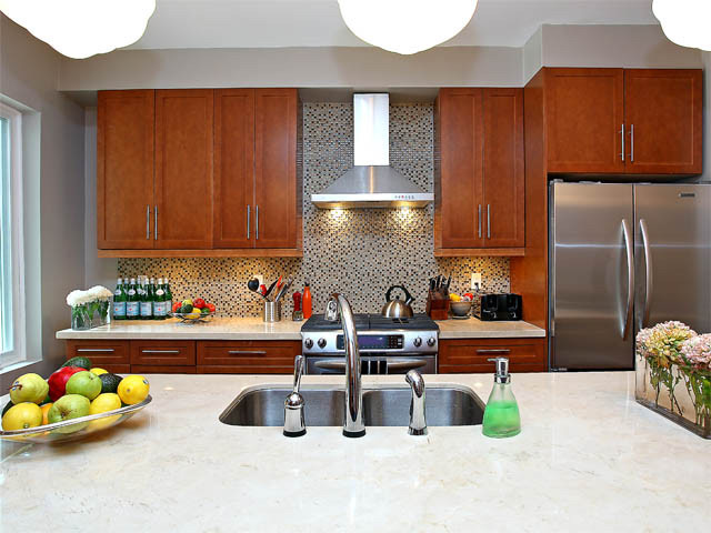 Inspiration for a large transitional galley medium tone wood floor and multicolored floor kitchen remodel in Toronto with a double-bowl sink, shaker cabinets, medium tone wood cabinets, quartz countertops, multicolored backsplash, glass tile backsplash, stainless steel appliances and an island