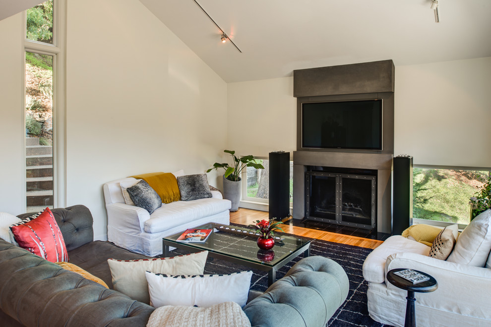 Mid-sized contemporary open concept living room in San Francisco with white walls, medium hardwood floors, a concrete fireplace surround and a wall-mounted tv.