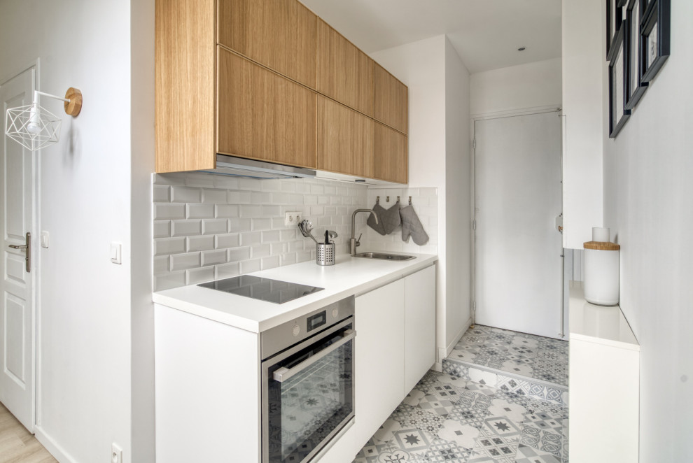 Inspiration for a small scandinavian single-wall open plan kitchen in Marseille with an undermount sink, medium wood cabinets, laminate benchtops, white splashback, subway tile splashback, panelled appliances, grey floor, white benchtop, recessed and cement tiles.