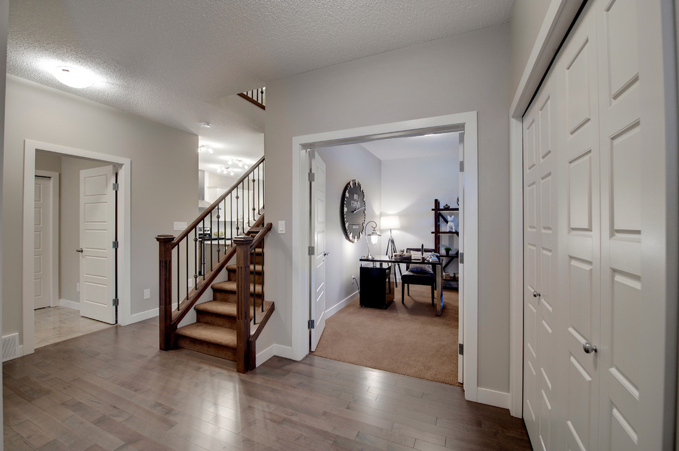 Foyer - mid-sized transitional medium tone wood floor foyer idea in Edmonton with beige walls and a white front door