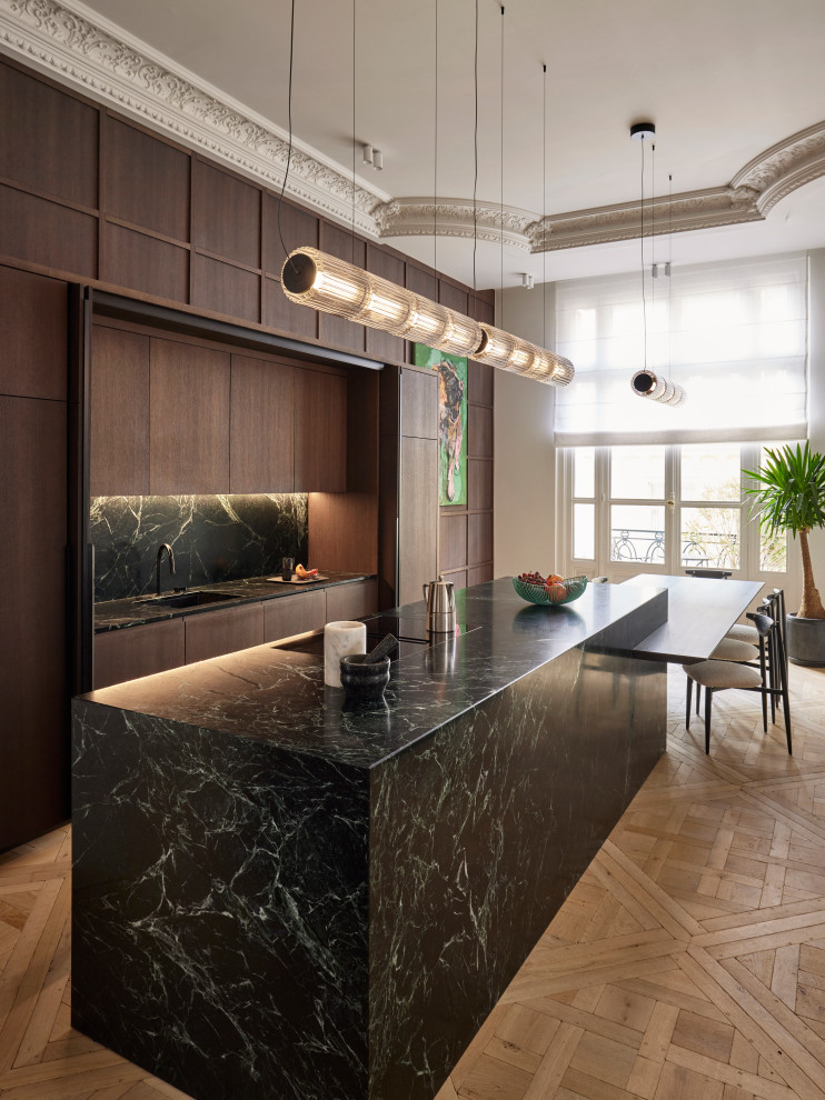 Réalisation d'une cuisine parallèle et encastrable design en bois foncé avec un évier encastré, un placard à porte plane, une crédence noire, une crédence en dalle de pierre, parquet clair, îlot, un sol beige, plan de travail noir et un plafond décaissé.