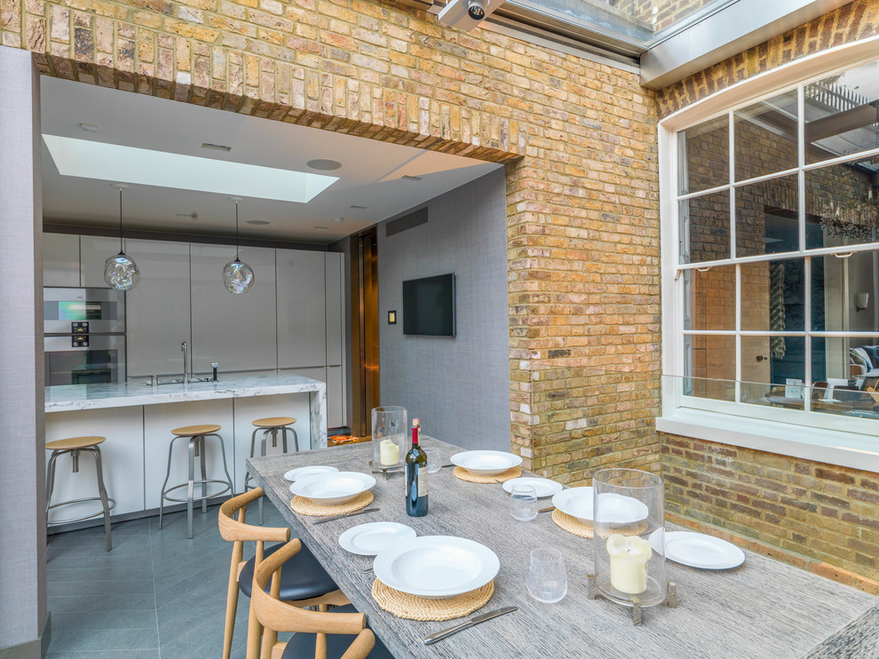 Large contemporary open plan dining in London with yellow walls, limestone floors and grey floor.