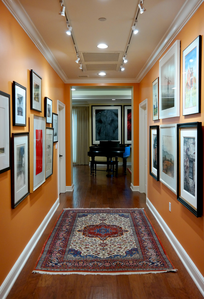This is an example of a mid-sized transitional hallway in Other with orange walls, dark hardwood floors and brown floor.