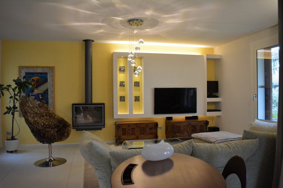 Idée de décoration pour une salle de séjour bohème de taille moyenne et fermée avec un mur jaune, un sol en carrelage de porcelaine, cheminée suspendue, un manteau de cheminée en métal, un téléviseur fixé au mur et un sol blanc.