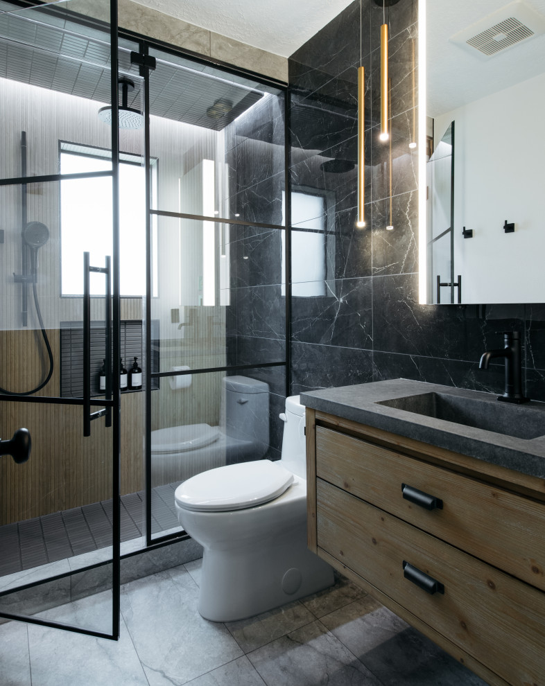 Inspiration for a contemporary 3/4 bathroom in Houston with flat-panel cabinets, medium wood cabinets, a floating vanity, an alcove shower, a one-piece toilet, black tile, an integrated sink, grey floor, a hinged shower door, grey benchtops and a single vanity.
