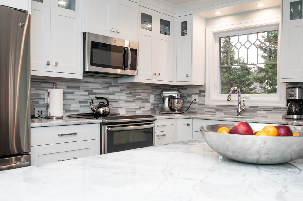 Example of a mid-sized transitional l-shaped ceramic tile and white floor eat-in kitchen design with an undermount sink, shaker cabinets, white cabinets, quartzite countertops, gray backsplash, stone tile backsplash, stainless steel appliances and an island
