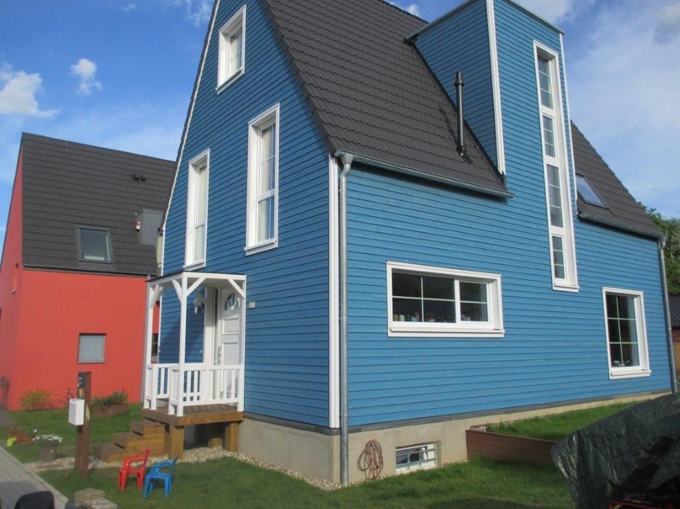 Mid-sized scandinavian two-storey blue house exterior in Other with wood siding, a gable roof and a tile roof.