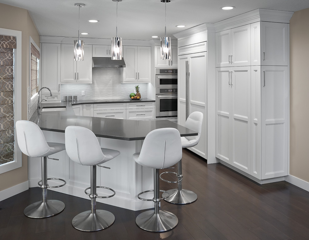 Eat-in kitchen - mid-sized transitional single-wall dark wood floor eat-in kitchen idea in Edmonton with an undermount sink, recessed-panel cabinets, white cabinets, quartz countertops, white backsplash, stainless steel appliances and a peninsula