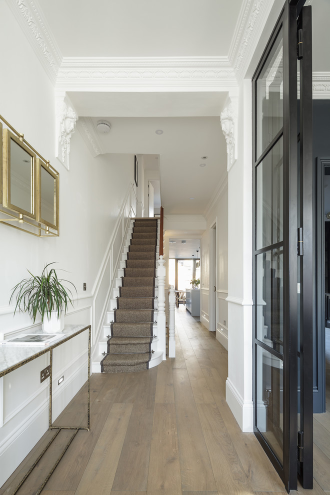 Inspiration for a mid-sized transitional hallway in London with white walls, medium hardwood floors and beige floor.