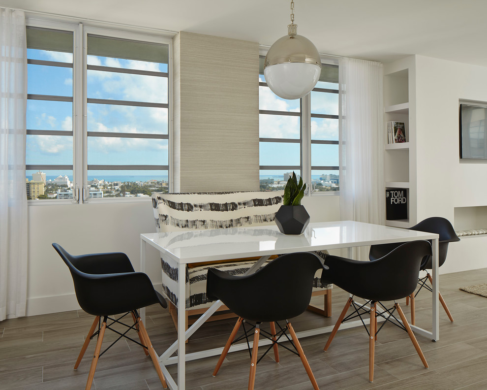 Photo of a contemporary kitchen/dining combo in Miami with white walls and light hardwood floors.