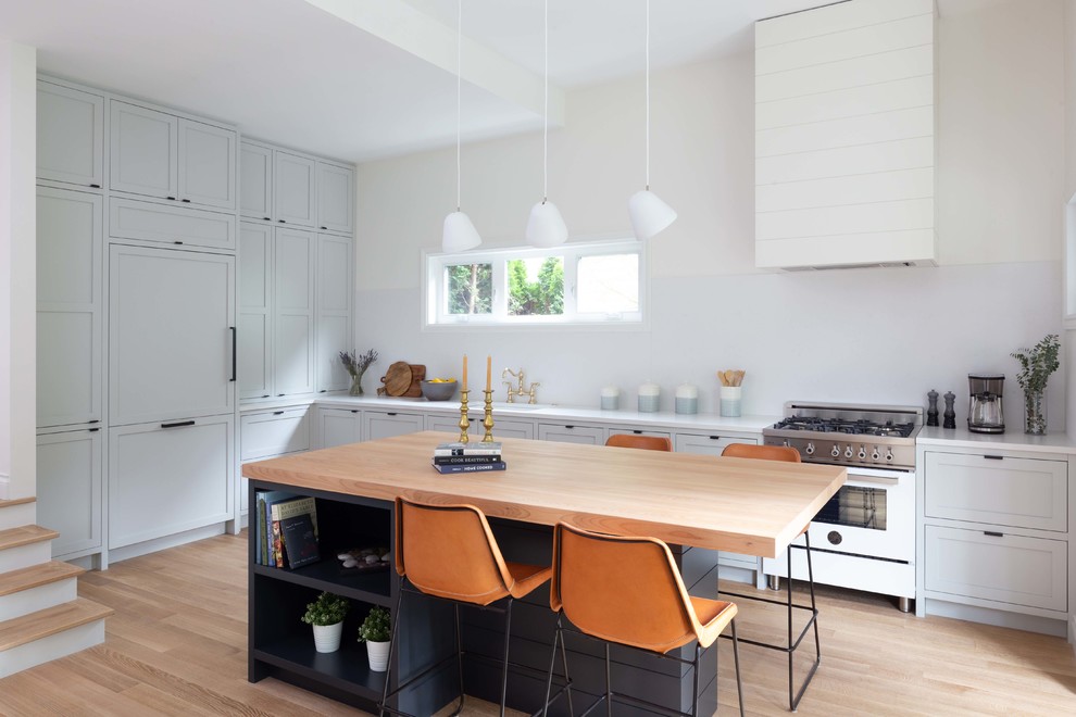 This is an example of a beach style l-shaped kitchen in Vancouver with shaker cabinets, grey cabinets, white splashback, panelled appliances, with island, white benchtop, a single-bowl sink, light hardwood floors and beige floor.