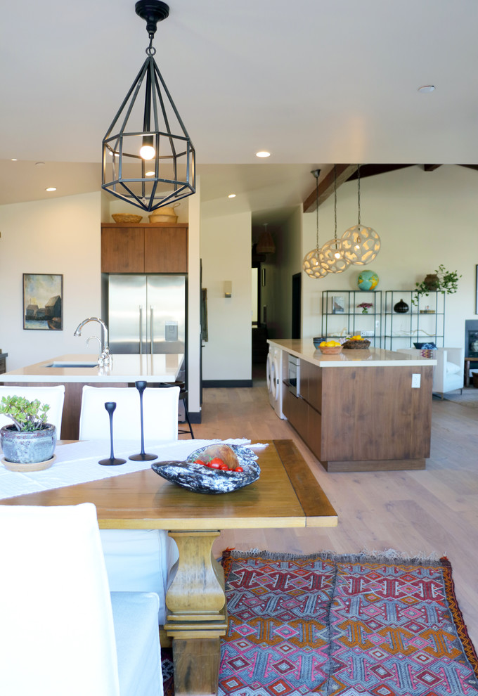 This is an example of a large eclectic open plan dining in Los Angeles with white walls, medium hardwood floors, a standard fireplace, a concrete fireplace surround and brown floor.