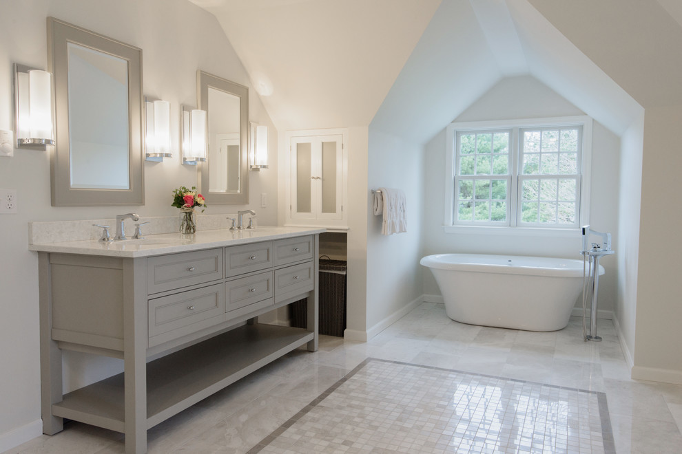 Photo of a large traditional master bathroom in Bridgeport with recessed-panel cabinets, grey cabinets, a freestanding tub, a double shower, a one-piece toilet, gray tile, stone tile, grey walls, marble floors, an undermount sink and marble benchtops.