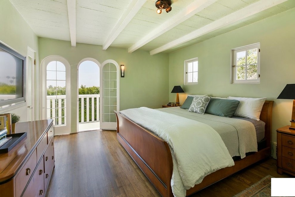 This is an example of a mid-sized traditional master bedroom in Los Angeles with green walls, laminate floors, no fireplace and brown floor.