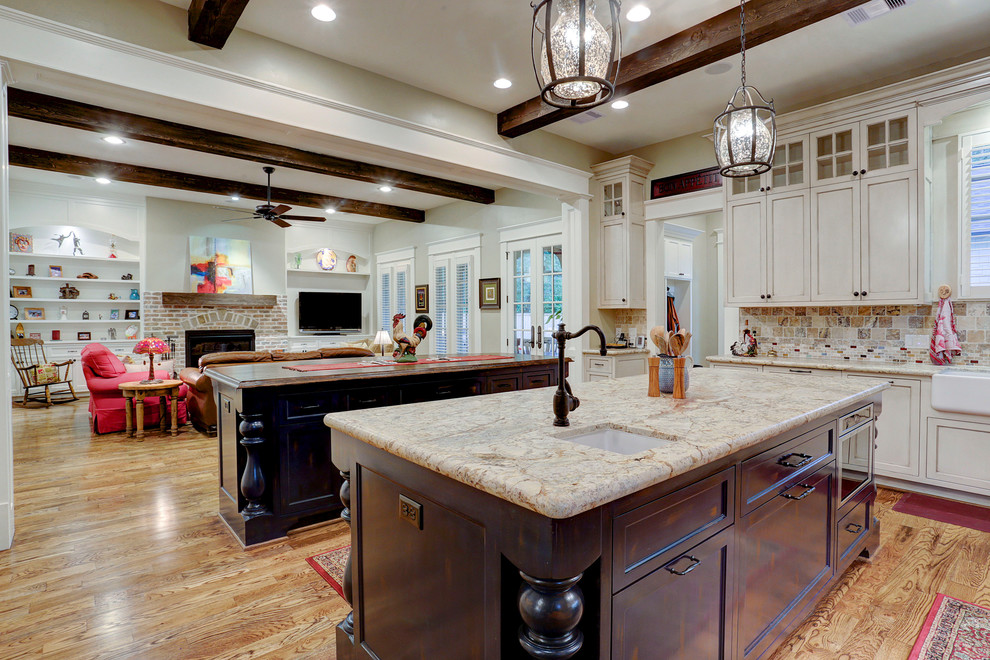 Design ideas for a large open plan kitchen in Houston with a farmhouse sink, white cabinets, medium hardwood floors, multiple islands, brown floor, beige benchtop, exposed beam and shaker cabinets.