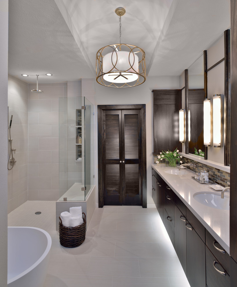Design ideas for a transitional bathroom in Houston with an undermount sink, flat-panel cabinets, dark wood cabinets, solid surface benchtops, a freestanding tub, a curbless shower, gray tile, porcelain tile and porcelain floors.