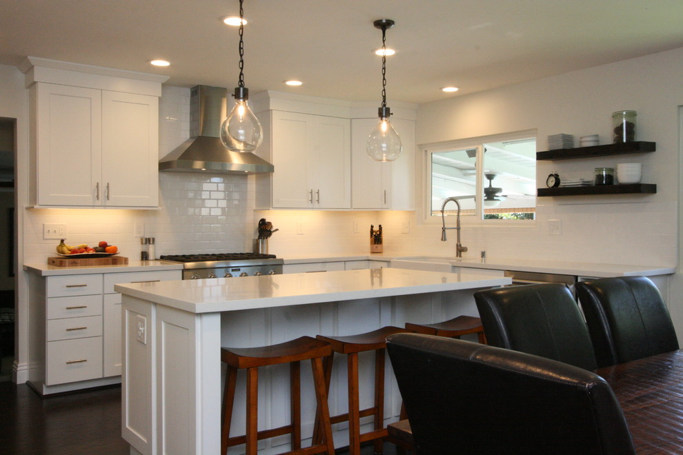 Eat-in kitchen - large transitional u-shaped dark wood floor eat-in kitchen idea in Orange County with a farmhouse sink, shaker cabinets, white cabinets, quartz countertops, white backsplash, ceramic backsplash, stainless steel appliances and an island