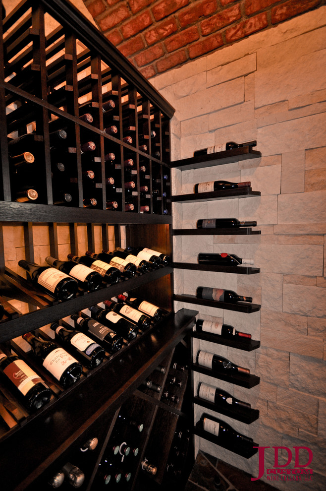 This is an example of a small traditional wine cellar in San Diego with limestone floors and display racks.