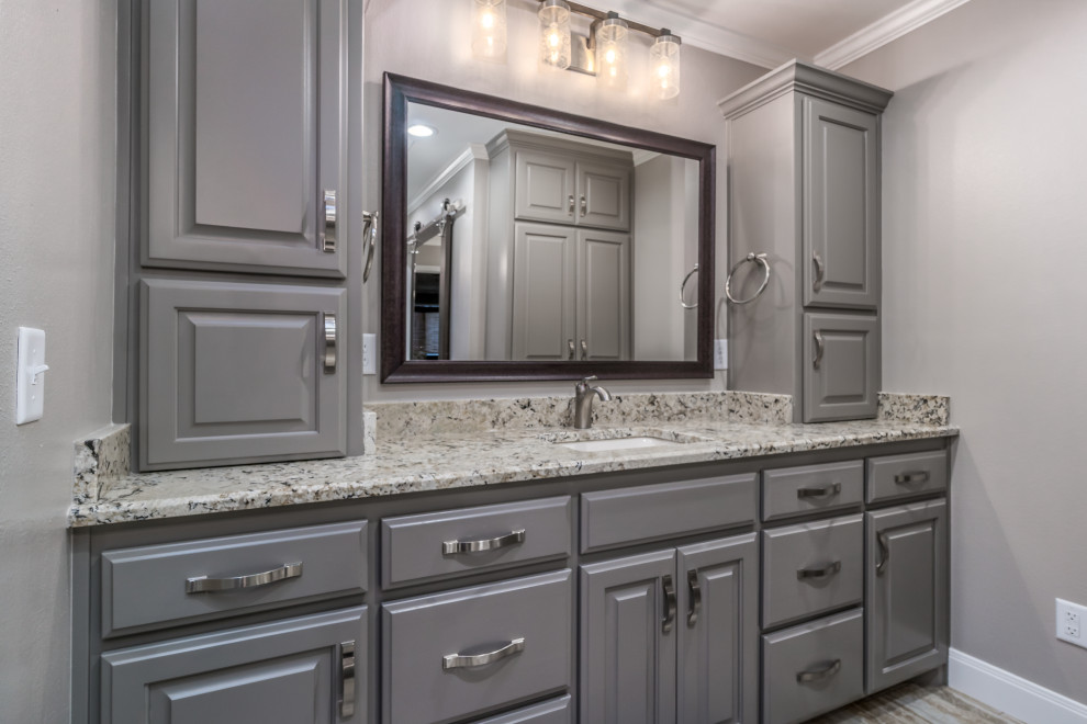 Example of a large transitional master porcelain tile porcelain tile and double-sink corner shower design with raised-panel cabinets, gray cabinets, a two-piece toilet, beige walls, an undermount sink, granite countertops and a built-in vanity