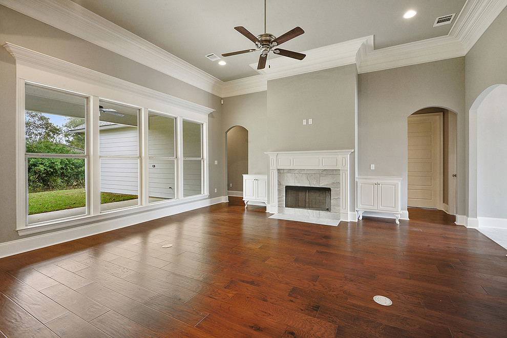 Traditional open concept living room in New Orleans with grey walls, medium hardwood floors, a standard fireplace and a tile fireplace surround.