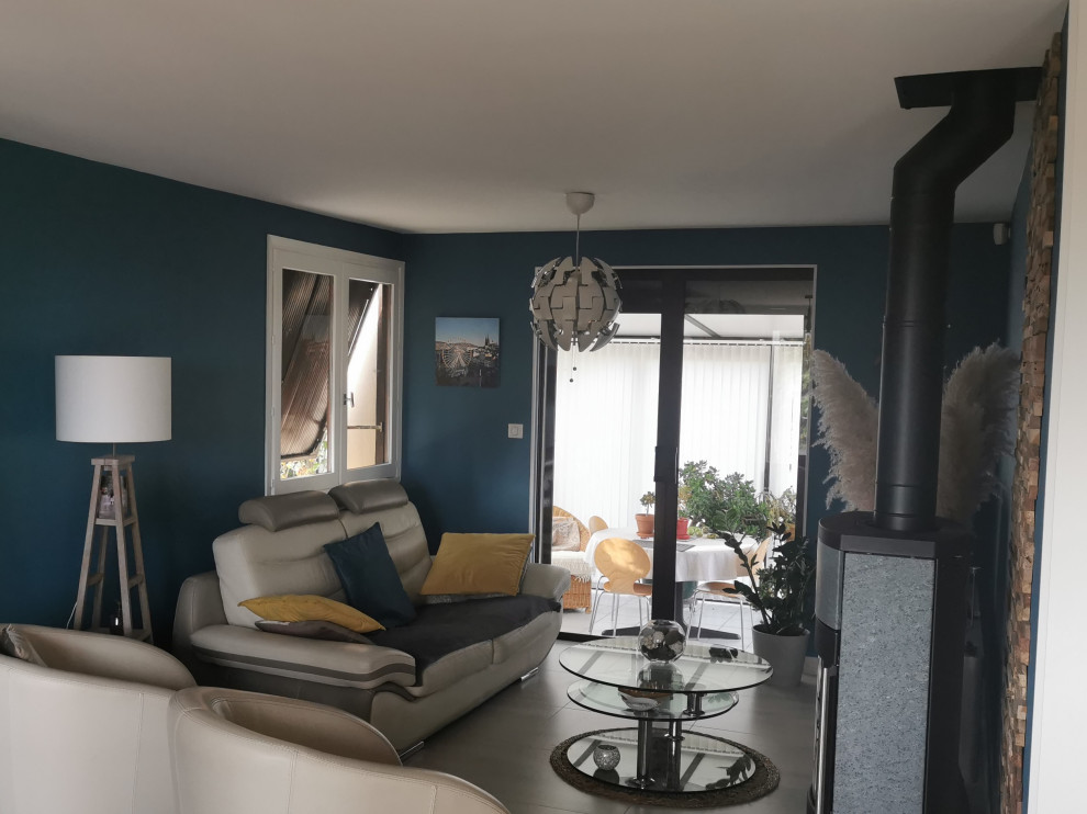 Mittelgroßes, Offenes Modernes Wohnzimmer mit blauer Wandfarbe, Keramikboden, Kaminofen und grauem Boden in Clermont-Ferrand
