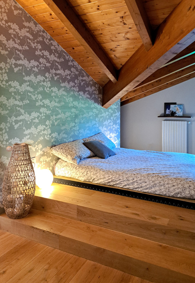 На фото: большая хозяйская спальня на мансарде в скандинавском стиле с серыми стенами, светлым паркетным полом, балками на потолке и обоями на стенах
