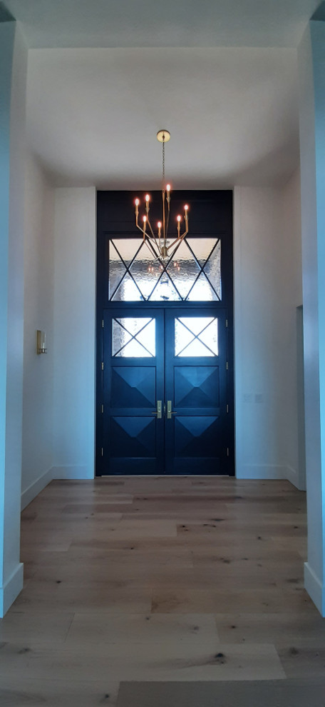 Idée de décoration pour une grande porte d'entrée tradition avec un mur blanc, parquet clair, une porte double, une porte marron et un sol marron.