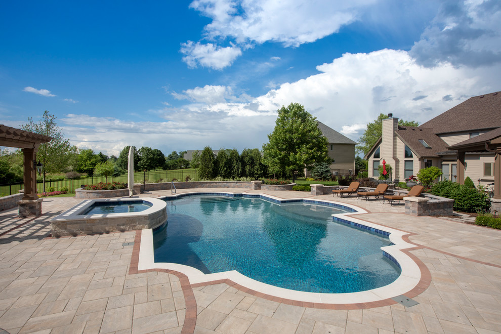 Mid-sized mediterranean backyard custom-shaped lap pool in Chicago with a hot tub and concrete pavers.
