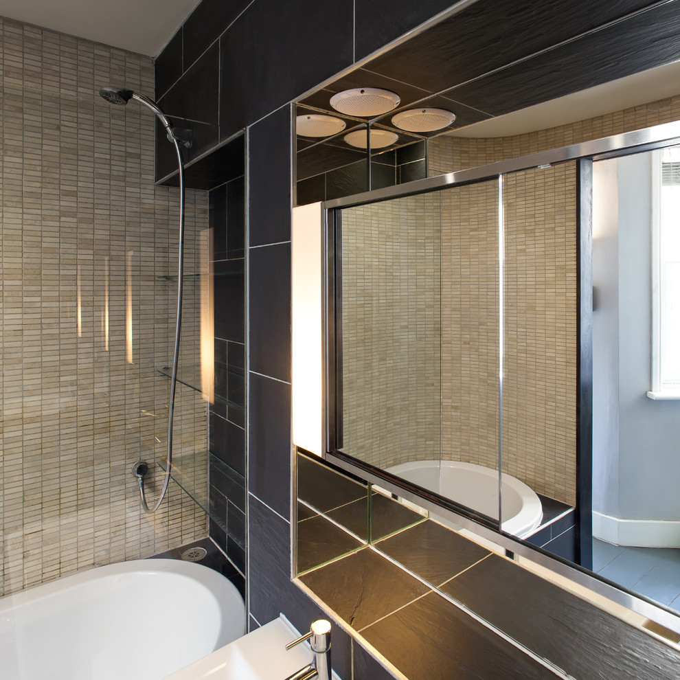 Design ideas for a small transitional kids bathroom in London with flat-panel cabinets, a drop-in tub, a shower/bathtub combo, a wall-mount toilet, black tile, ceramic tile, beige walls, ceramic floors, a wall-mount sink, tile benchtops, black floor, an open shower and black benchtops.