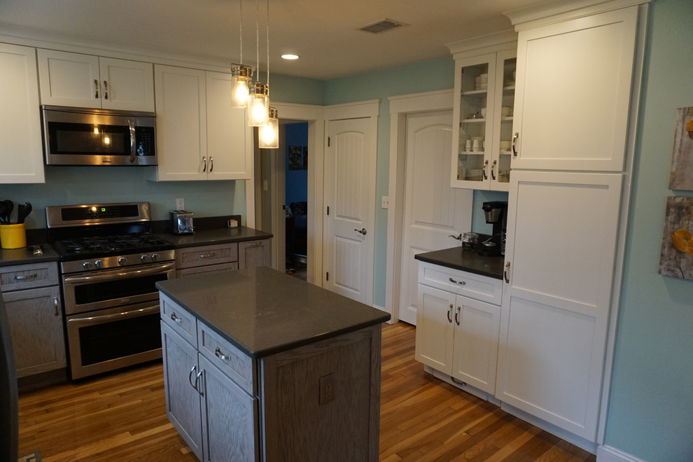 Example of a mid-sized transitional u-shaped medium tone wood floor eat-in kitchen design in Boston with an undermount sink, shaker cabinets, gray cabinets, quartz countertops, black backsplash, stainless steel appliances and an island