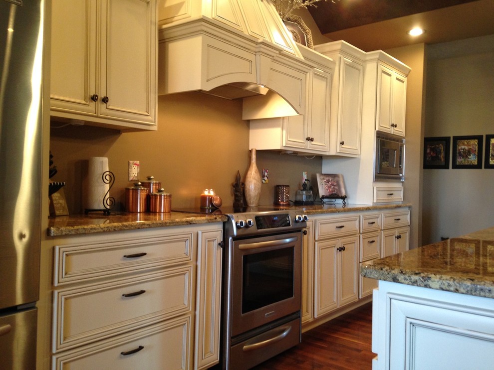 Large transitional l-shaped medium tone wood floor and brown floor kitchen pantry photo with recessed-panel cabinets, white cabinets, laminate countertops, stainless steel appliances and an island