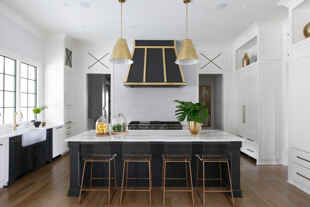 Inspiration for a beach style u-shaped open plan kitchen in Nashville with a farmhouse sink, shaker cabinets, black cabinets, white splashback, panelled appliances, medium hardwood floors, with island and brown floor.