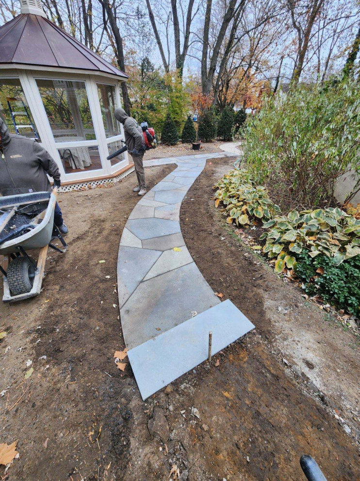 Inspiration for a mid-sized backyard partial sun formal garden for winter in New York with natural stone pavers and a metal fence.