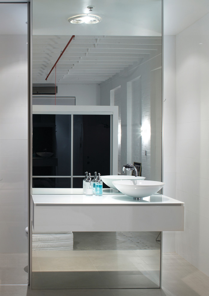This is an example of a small industrial master bathroom in Perth with a vessel sink, flat-panel cabinets, white cabinets, glass benchtops, an alcove shower, a one-piece toilet, white tile, porcelain tile, white walls and ceramic floors.