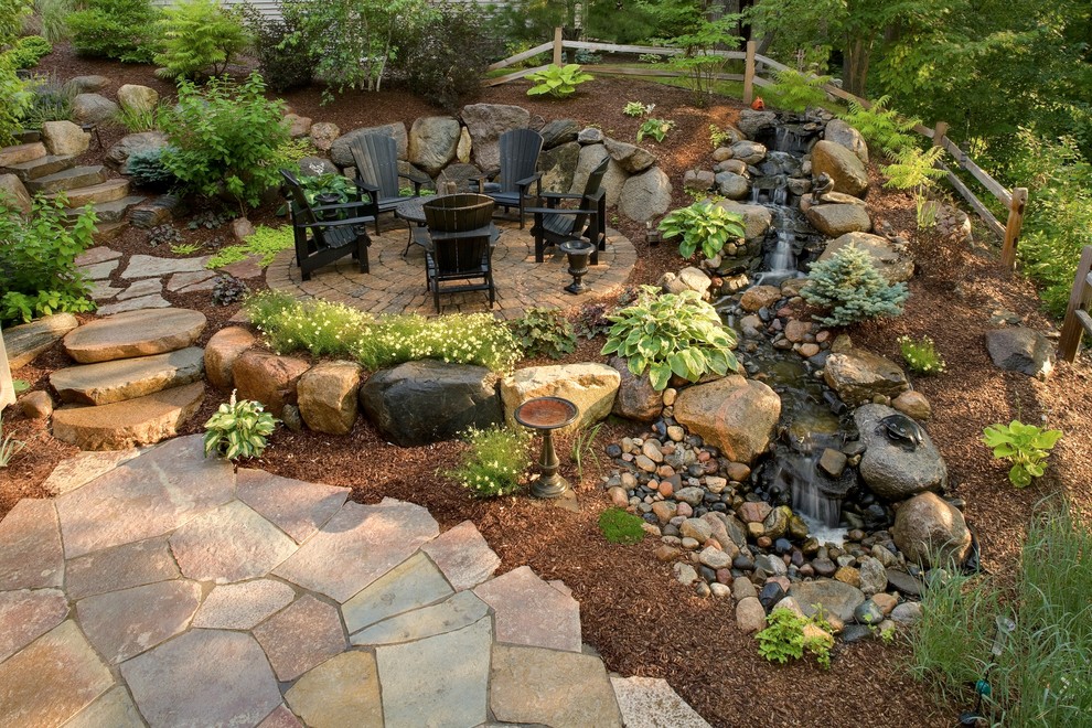 Design ideas for a mid-sized traditional backyard garden in Minneapolis with a fire feature and natural stone pavers.