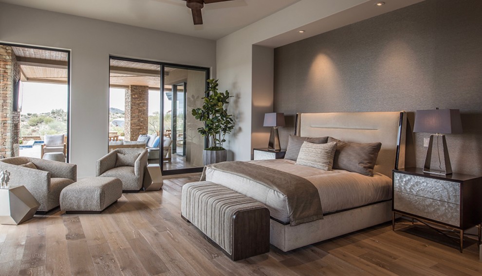 This is an example of a large contemporary master bedroom in Phoenix with beige walls, medium hardwood floors, a ribbon fireplace, a concrete fireplace surround and beige floor.