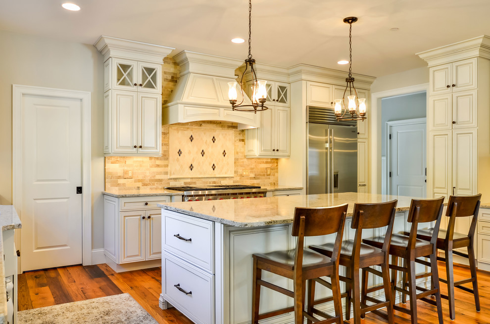 This is an example of a large traditional u-shaped eat-in kitchen in Boston with an undermount sink, raised-panel cabinets, white cabinets, quartz benchtops, beige splashback, stainless steel appliances and with island.