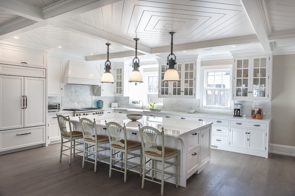 Large transitional l-shaped medium tone wood floor and brown floor eat-in kitchen photo in Boston with a farmhouse sink, shaker cabinets, white cabinets, gray backsplash, paneled appliances, an island, marble countertops and marble backsplash