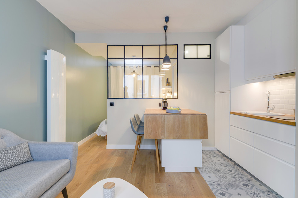 Scandinavian open plan kitchen in Other with a drop-in sink, flat-panel cabinets, white cabinets, wood benchtops, white splashback, subway tile splashback, a peninsula and multi-coloured floor.