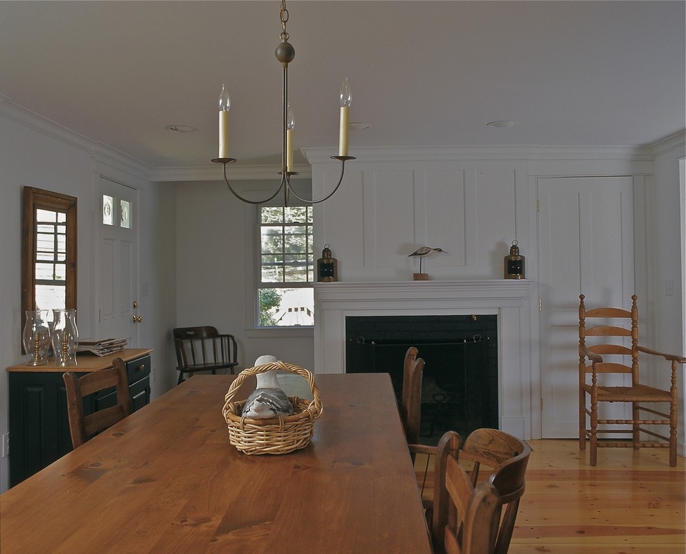 Photo of a large traditional separate dining room in Boston with white walls, medium hardwood floors, a standard fireplace and brown floor.