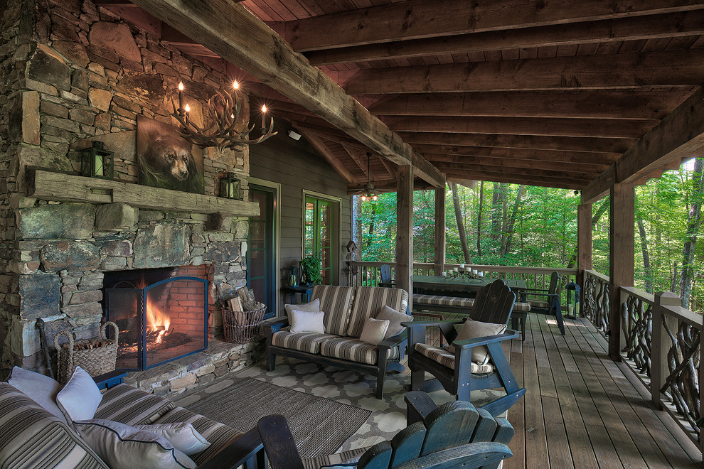 Mountain style deck photo with a roof extension and a fireplace