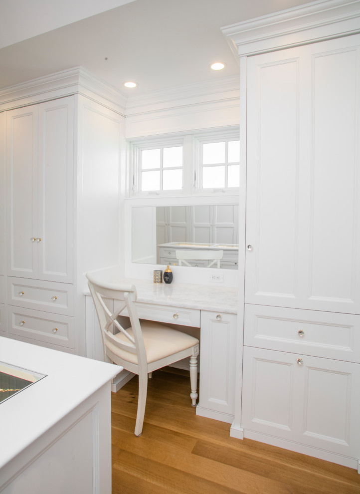Photo of a large beach style women's dressing room in Philadelphia with recessed-panel cabinets, white cabinets, medium hardwood floors and brown floor.